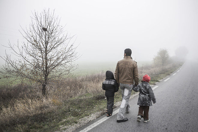 Bild von einem Vater mit zwei kleinen Kindern an der Hand auf einer einsamen Landstraße, die ins Nirgendwo zu führen scheint.
