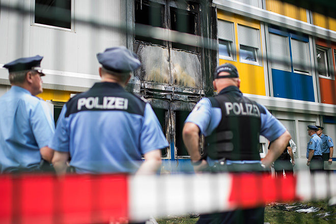 Bild: Anschlag auf eine Flüchtlingsunterkunft in Berlin-Buch: Polizisten begutachten die Brandstelle, Aug. 2016